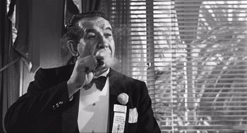 Movie still from “Some Like It Hot” (1959), directed by Billy Wilder – An older man smoking a cigarette in front of a window; Close Up shot, Over the shoulder angle