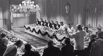 Movie still from “Some Like It Hot” (1959), directed by Billy Wilder – A black and white photo of a group of people sitting at a table; Wide shot, Over the shoulder angle