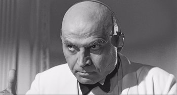 Movie still from “Some Like It Hot” (1959), directed by Billy Wilder – An older bald man wearing a white shirt and a bow tie; Close Up shot, Low angle