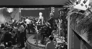Movie still from “Some Like It Hot” (1959), directed by Billy Wilder – A black and white photo of people sitting on a stage; Extreme Wide shot, High angle