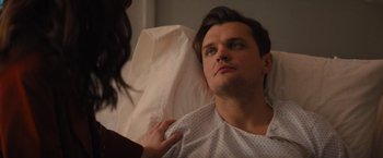 Movie still from “Something from Tiffany's” (2022), directed by Daryl Wein – A man in a hospital gown is being comforted by a woman; Close Up shot, Over the shoulder angle