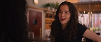 Movie still from “Something from Tiffany's” (2022), directed by Daryl Wein – A young woman smiles while sitting at a table in a restaurant; Close Up shot, Over the shoulder angle