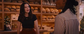 Movie still from “Something from Tiffany's” (2022), directed by Daryl Wein – A woman standing in front of a man in a bakery; Medium shot, Over the shoulder angle