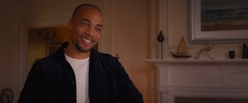 Movie still from “Something from Tiffany's” (2022), directed by Daryl Wein – A man sitting in front of a fireplace smiling for the camera; Close Up shot, Over the shoulder angle