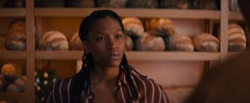 Movie still from “Something from Tiffany's” (2022), directed by Daryl Wein – A woman with dreadlocks standing in front of a shelf of bread; Close Up shot, Over the shoulder angle