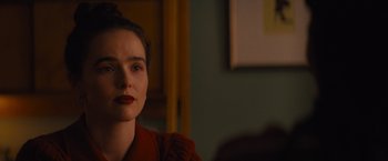 Movie still from “Something from Tiffany's” (2022), directed by Daryl Wein – A woman in a red jacket sitting in front of a painting; Close Up shot, Over the shoulder angle