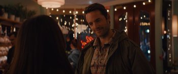 Movie still from “Something from Tiffany's” (2022), directed by Daryl Wein – A person standing in a room with lights in the background; Close Up shot, Over the shoulder angle