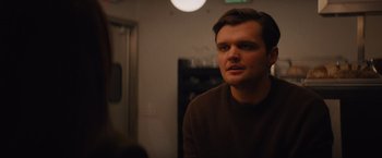 Movie still from “Something from Tiffany's” (2022), directed by Daryl Wein – A man in a brown sweater looking at the camera; Close Up shot, Over the shoulder angle