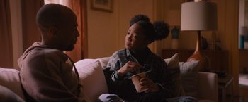 Movie still from “Something from Tiffany's” (2022), directed by Daryl Wein – Two people are sitting on a couch and one of them is holding a cup; Medium shot, Over the shoulder angle