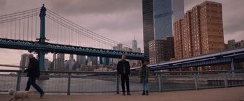 Movie still from “Something from Tiffany's” (2022), directed by Daryl Wein – Two people standing next to each other near a river; Wide shot, Low angle