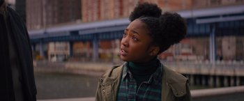 Movie still from “Something from Tiffany's” (2022), directed by Daryl Wein – A young woman looking up while standing next to a river; Close Up shot, Over the shoulder angle