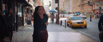 Movie still from “Something from Tiffany's” (2022), directed by Daryl Wein – A woman is walking down the street talking on a phone; Medium shot, Over the shoulder angle