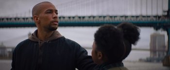 Movie still from “Something from Tiffany's” (2022), directed by Daryl Wein – A man standing next to another man in front of a bridge; Close Up shot, Low angle