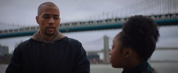 Movie still from “Something from Tiffany's” (2022), directed by Daryl Wein – A man and a woman are standing next to each other in front of a bridge; Close Up shot, Over the shoulder angle
