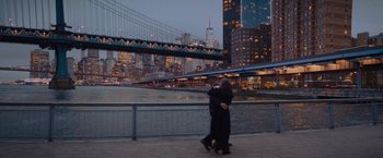 Movie still from “Something from Tiffany's” (2022), directed by Daryl Wein – Two people are hugging on a bridge over a body of water at night; Extreme Wide shot, Over the shoulder angle