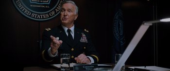 Movie still from “Sonic the Hedgehog” (2020), directed by Jeff Fowler – A man in a military uniform sitting at a table; Medium shot, Over the shoulder angle