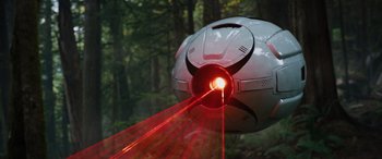 Movie still from “Sonic the Hedgehog” (2020), directed by Jeff Fowler – A red laser beam coming out of a soccer ball in the woods; Extreme Wide shot, Low angle