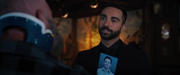 Movie still from “Sonic the Hedgehog” (2020), directed by Jeff Fowler – A man holding a picture of a man in front of a wall; Close Up shot, Over the shoulder angle