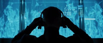 Movie still from “Sonic the Hedgehog” (2020), directed by Jeff Fowler – A man with headphones in front of a large screen; Close Up shot, Over the shoulder angle