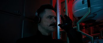 Movie still from “Sonic the Hedgehog” (2020), directed by Jeff Fowler – A man with a mustache wearing a pair of headphones; Close Up shot, Low angle