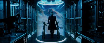 Movie still from “Sonic the Hedgehog” (2020), directed by Jeff Fowler – A man standing in front of an image of a space station; Wide shot, Low angle