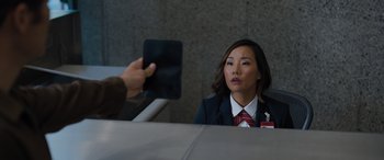 Movie still from “Sonic the Hedgehog” (2020), directed by Jeff Fowler – A person taking a picture of a woman in a business suit; Close Up shot, Over the shoulder angle