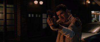 Movie still from “Sonic the Hedgehog” (2020), directed by Jeff Fowler – A man is holding a gun in a dark room; Medium shot, Over the shoulder angle