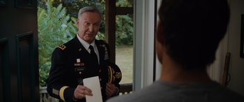 Movie still from “Sonic the Hedgehog” (2020), directed by Jeff Fowler – An older man in a military uniform holding papers; Medium shot, Over the shoulder angle