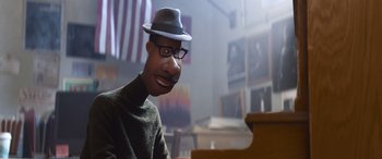 Movie still from “Soul” (2020), directed by Kemp Powers – A man in a hat and glasses sitting at a piano; Close Up shot, High angle