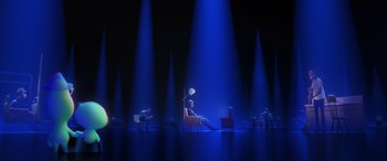 Movie still from “Soul” (2020), directed by Kemp Powers – A man sitting on a chair in a room lit by blue lights; Extreme Wide shot, High angle