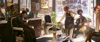 Movie still from “Soul” (2020), directed by Kemp Powers – An old fashioned barber shop with a barber chair and a smiling man; Wide shot, Over the shoulder angle