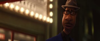 Movie still from “Soul” (2020), directed by Kemp Powers – A man with a hat and glasses is standing in front of a movie screen; Close Up shot, Over the shoulder angle