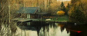 Movie still from “Soulcatcher” (2023), directed by Daniel Markowicz – A house sitting next to a body of water; Extreme Wide shot, High angle