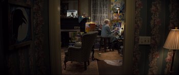 Movie still from “Brightburn” (2019), directed by David Yarovesky – Two people sitting at a table in front of a painting; Wide shot, High angle