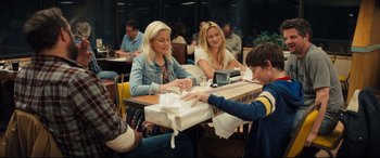 Movie still from “Brightburn” (2019), directed by David Yarovesky – A young boy is handing a gift to a woman; Medium shot, Over the shoulder angle