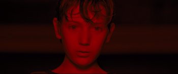 Movie still from “Brightburn” (2019), directed by David Yarovesky – A young man with red lighting on his face; Close Up shot, High angle