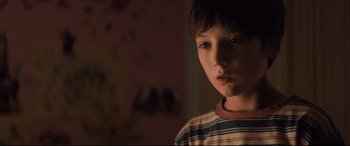 Movie still from “Brightburn” (2019), directed by David Yarovesky – A young boy is standing in the dark; Close Up shot, Over the shoulder angle