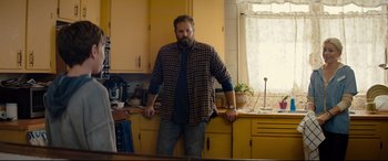 Movie still from “Brightburn” (2019), directed by David Yarovesky – A man standing in a kitchen next to a counter; Medium shot, Over the shoulder angle