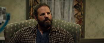 Movie still from “Brightburn” (2019), directed by David Yarovesky – A man sitting on a couch looking at the camera; Close Up shot, Over the shoulder angle