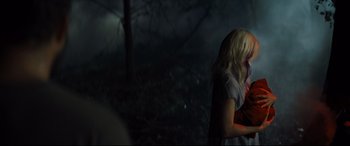 Movie still from “Brightburn” (2019), directed by David Yarovesky – A woman standing in the dark near a tree; Medium shot, Over the shoulder angle