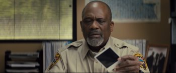 Movie still from “Brightburn” (2019), directed by David Yarovesky – A police officer looking at a photo of himself; Close Up shot, Over the shoulder angle