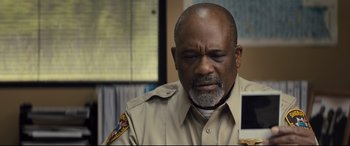 Movie still from “Brightburn” (2019), directed by David Yarovesky – A man in a police uniform is looking down; Close Up shot, High angle