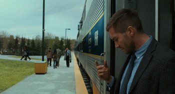 Movie still from “Source Code” (2011), directed by Duncan Jones – A man standing next to a train holding a cell phone; Medium shot, Over the shoulder angle