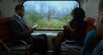 Movie still from “Source Code” (2011), directed by Duncan Jones – A man and a woman sitting on a train looking at cell phones; Medium shot, Over the shoulder angle
