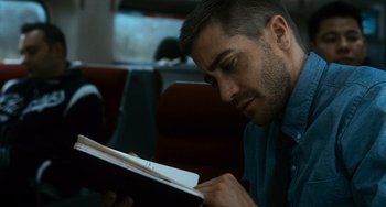 Movie still from “Source Code” (2011), directed by Duncan Jones – A man sitting on a train looking at a book; Close Up shot, Over the shoulder angle