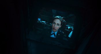 Movie still from “Source Code” (2011), directed by Duncan Jones – A picture of a woman in a uniform in a dark room; Close Up shot, High angle