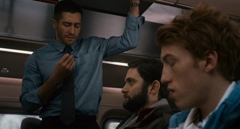 Movie still from “Source Code” (2011), directed by Duncan Jones – A man is tying a neck tie on a train; Medium shot, Over the shoulder angle