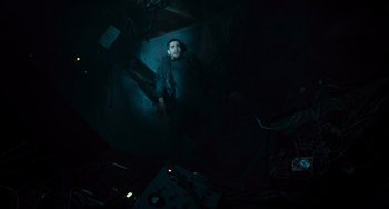 Movie still from “Source Code” (2011), directed by Duncan Jones – A man standing in the dark in a dark room; Wide shot, Overhead angle