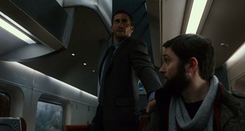 Movie still from “Source Code” (2011), directed by Duncan Jones – A man standing on a train next to another man; Medium shot, Over the shoulder angle