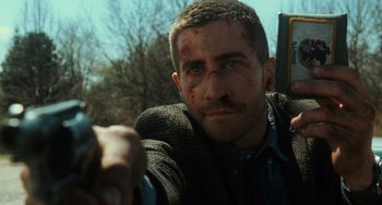 Movie still from “Source Code” (2011), directed by Duncan Jones – A person holding a gun; Close Up shot, Over the shoulder angle